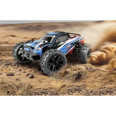 Une voiture télécommandée tout-terrain soulevant de la poussière. Le modèle présente des accents bleus et rouges et dispose de grandes roues qui tournent rapidement.