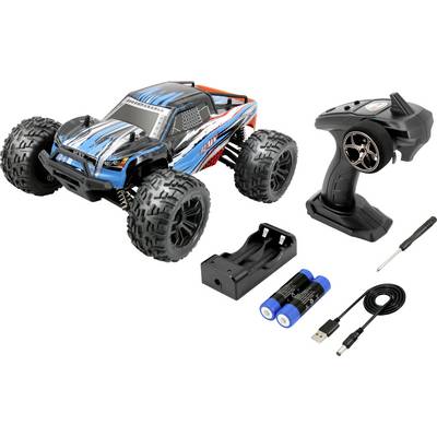 Voiture télécommandée jouet avec carrosserie bleue et grandes roues, à côté de sa télécommande, chargeur de batterie avec batteries, câble de charge et tournevis.