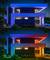 Maison moderne à deux étages de nuit, éclairée en bleu à l'étage supérieur, chaleureux éclairage au rez-de-chaussée, entourée d'arbres et de lumières de jardin.
