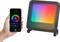 Une main tient un smartphone avec une application permettant de contrôler la lampe LED changeant de couleur, qui se trouve à côté. La lampe brille dans les couleurs de l'arc-en-ciel.