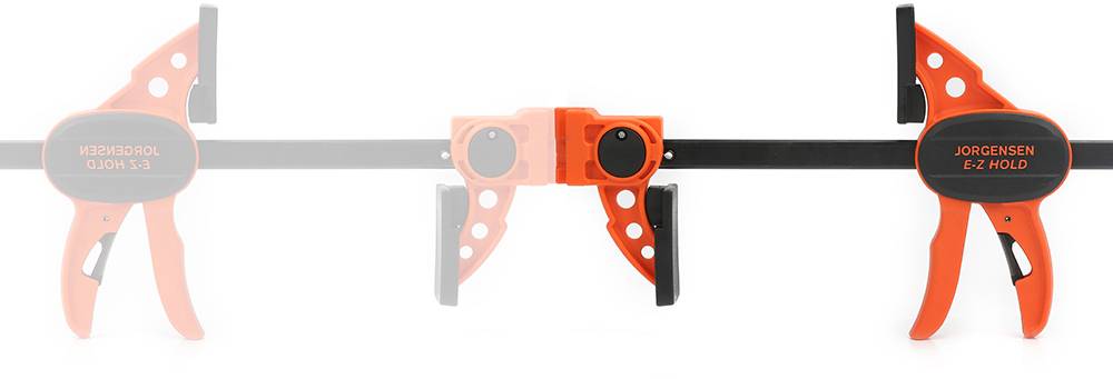 L'image montre un serre-joint orange portant l'inscription 'JORGENSEN E-Z HOLD', qui maintient un morceau de bois en place.