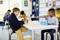 Deux garçons sont assis à une table dans la salle de classe et jouent avec des jouets colorés. En arrière-plan, d'autres enfants jouent.