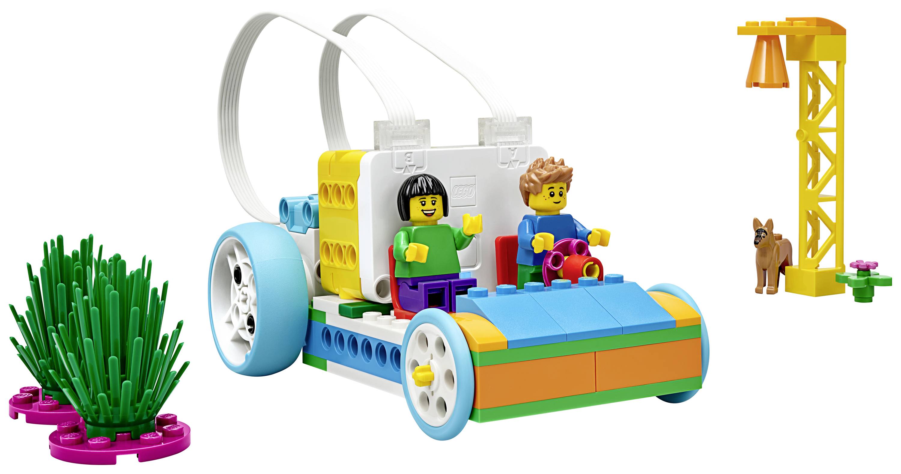 Une voiture LEGO colorée avec deux personnages, équipée d'un module de programmation. En arrière-plan, des plantes et une petite tour.