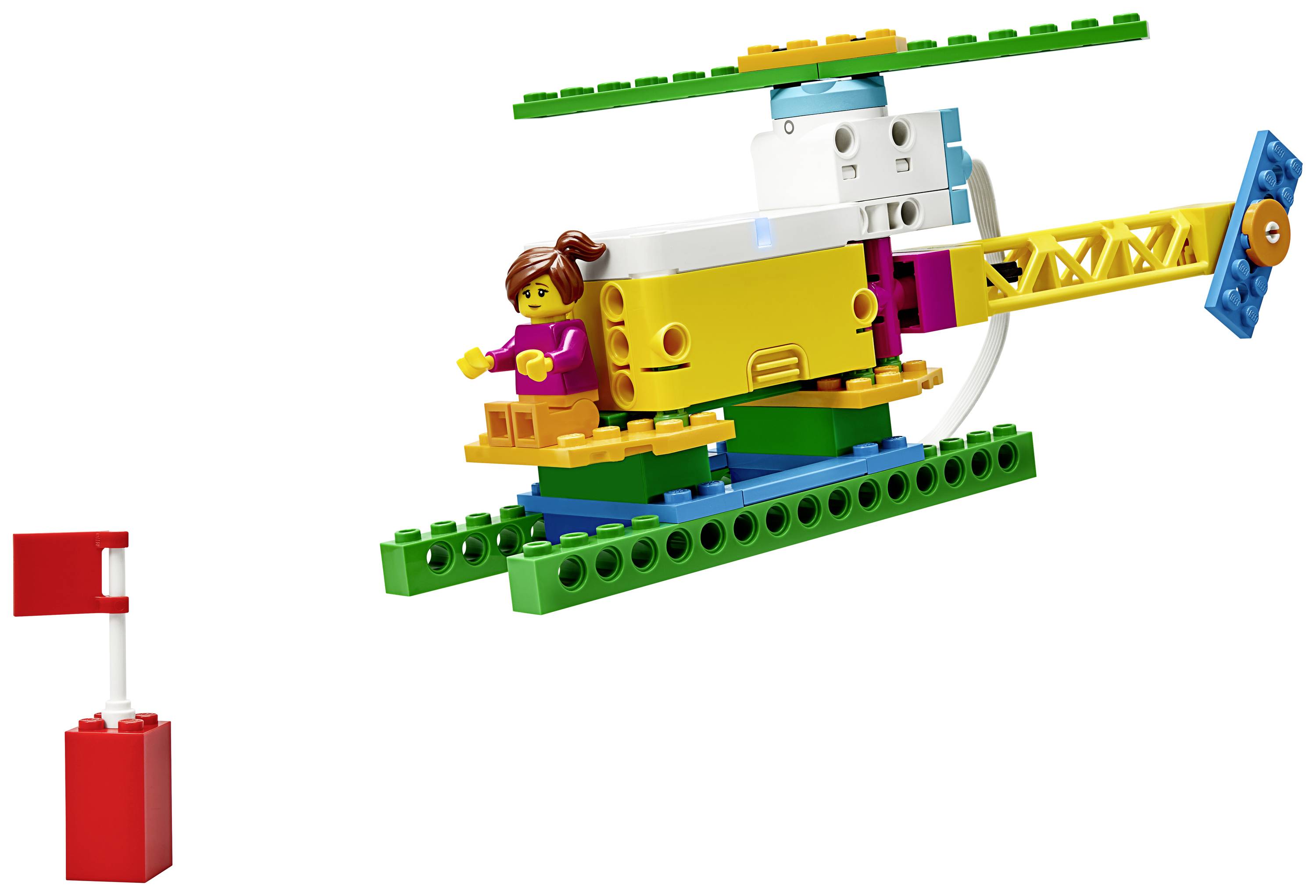Hélicoptère Lego coloré avec des pales de rotor, une queue jaune et une minifigurine à l'intérieur. À gauche, un morceau de drapeau Lego rouge sur un socle.