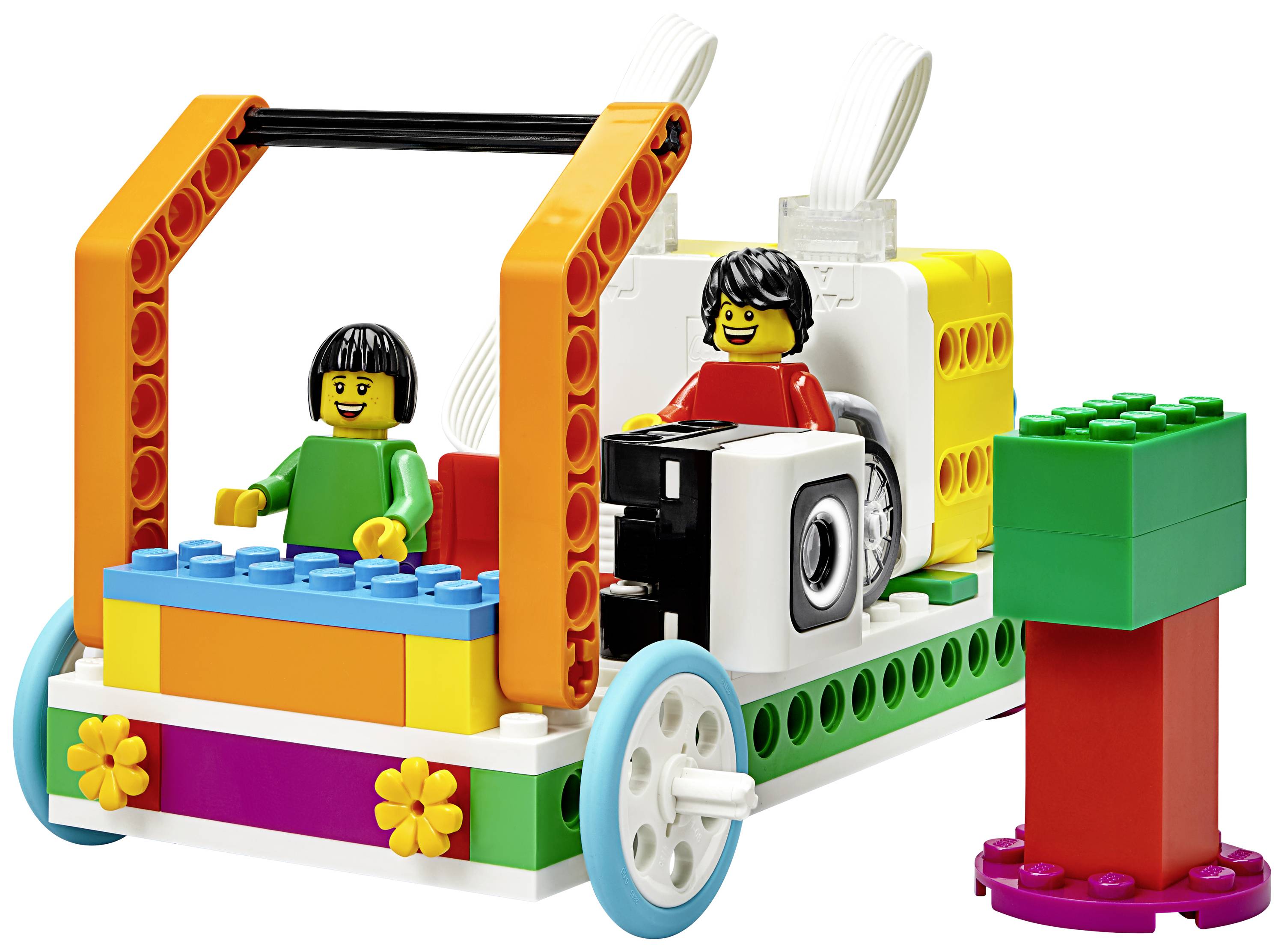 Une voiture colorée construite en briques LEGO, avec deux personnages à l'avant. La voiture a des roues et des pierres décoratives en forme de fleurs.
