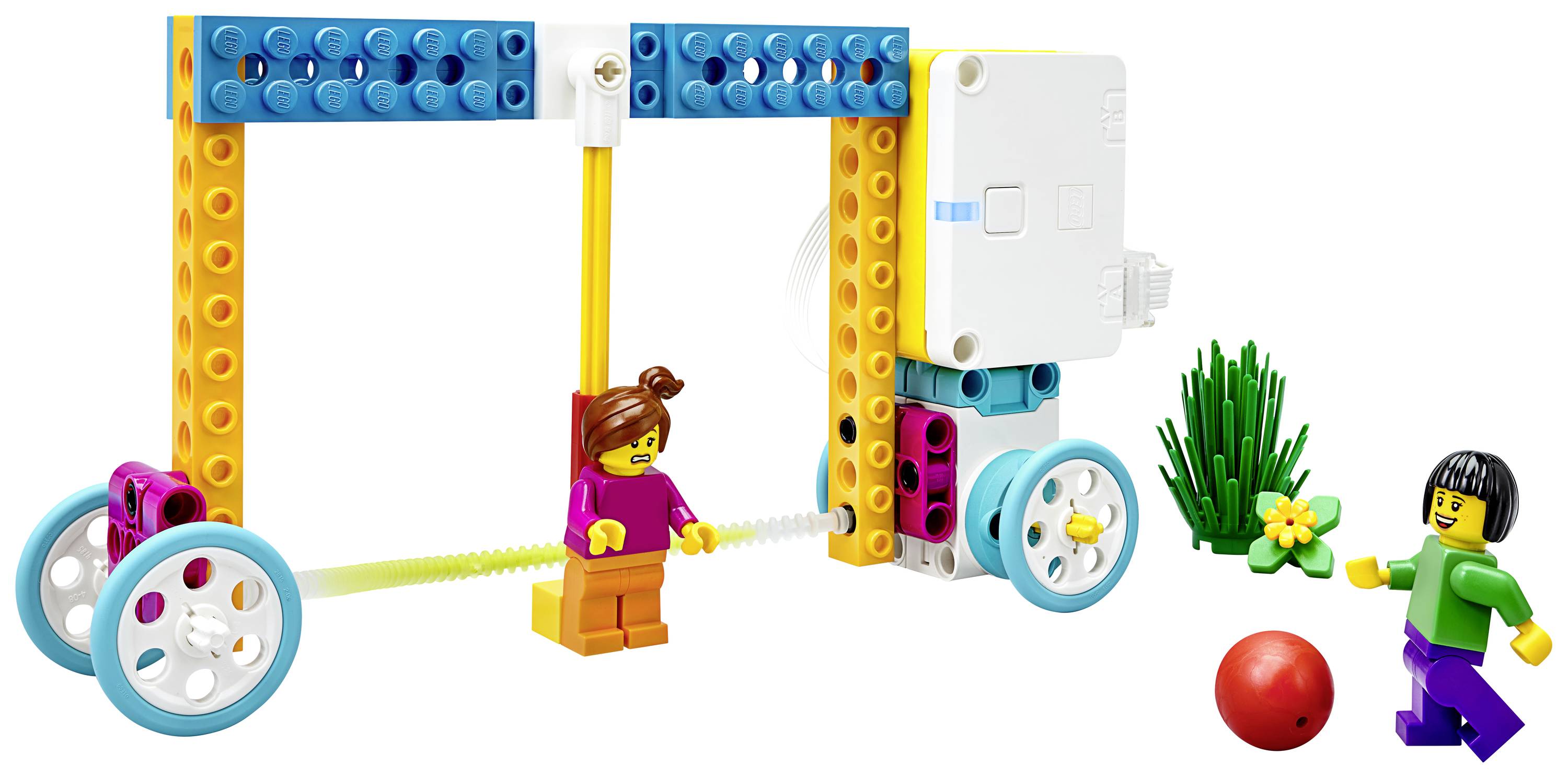 Modèle LEGO coloré assemblé avec des roues. Un enfant joue avec un ballon rouge et des plantes sont en arrière-plan.