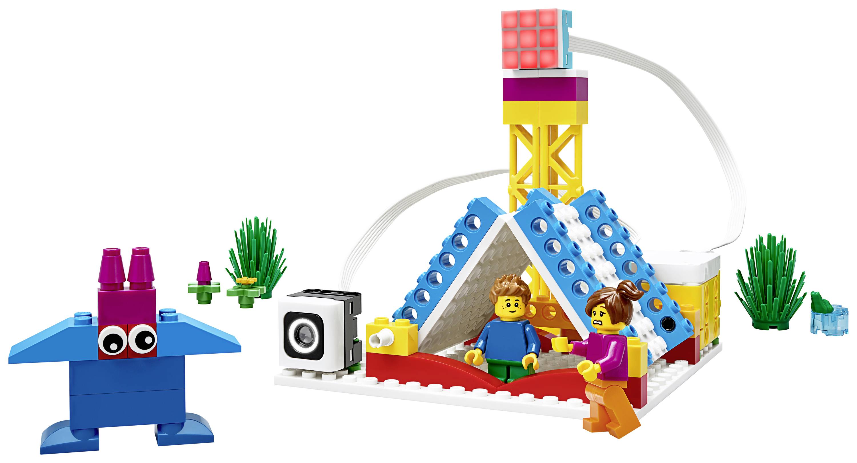 Un ensemble LEGO comprenant une pyramide, des figurines et des composants électroniques, entouré de plantes.