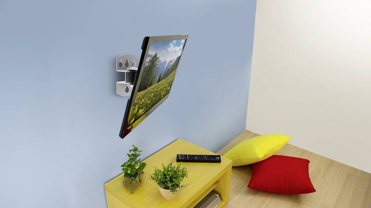 Un écran avec une image de nature, monté sur un mur bleu. En-dessous, une table jaune avec des plantes, à côté de coussins colorés posés sur le sol.