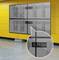 Mur vidéo composé de quatre écrans montés sur un mur jaune. Un agrandissement met en évidence les supports de fixation des écrans.