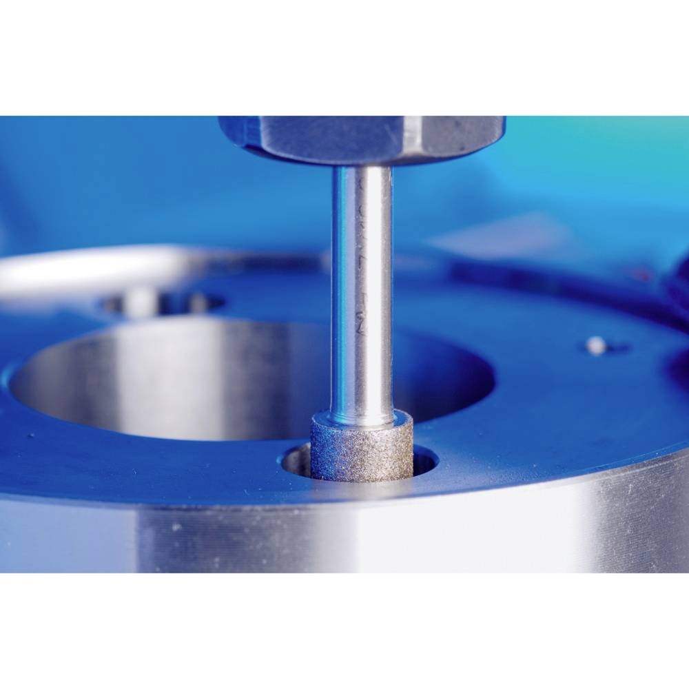 Gros plan sur une machine de précision usinant un composant métallique. Un outil cylindrique entre en contact avec la surface.