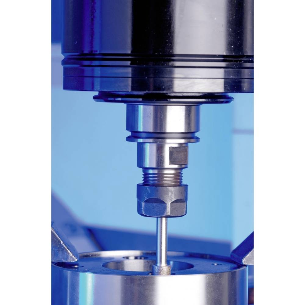 Une machine métallique fore avec précision dans une pièce, entourée d'un fond bleu.