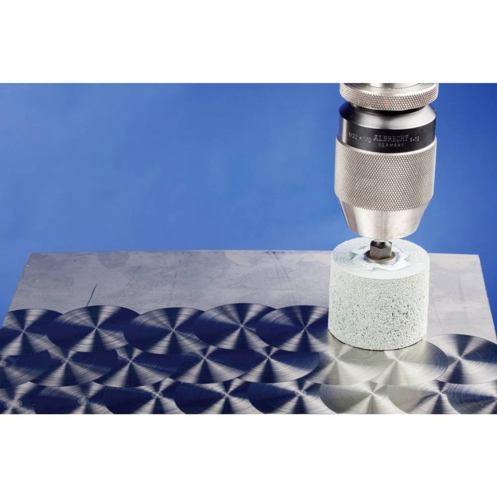 Un foret meule un matériau métallique avec une surface d'accessoire en forme de disque, présentant des motifs circulaires concentriques.