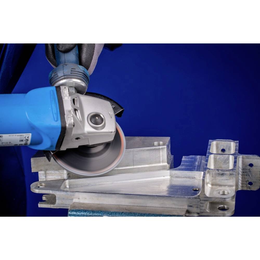 Une main tient une meuleuse d'angle qui travaille le métal. Des étincelles jaillissent de l'interface. L'arrière-plan est flou.