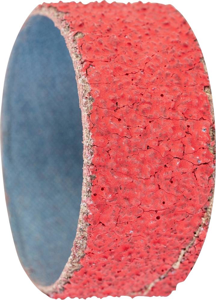 Gros plan d'un rouleau de bande abrasive granulée rouge sur un fond sombre. La mise au point est sur la surface texturée et craquelée.