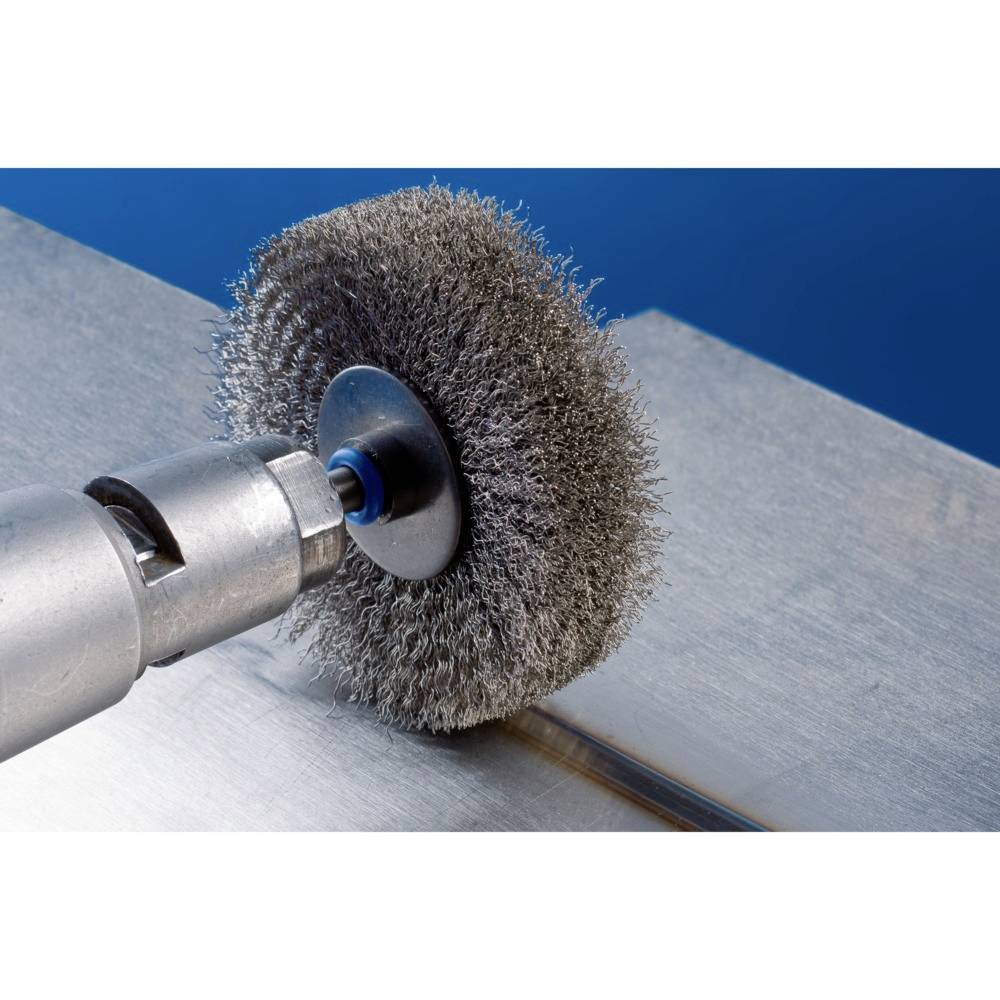 Un foret équipé d'une brosse métallique polit une surface métallique. La brosse tournant à grande vitesse élimine la saleté ou la rouille.