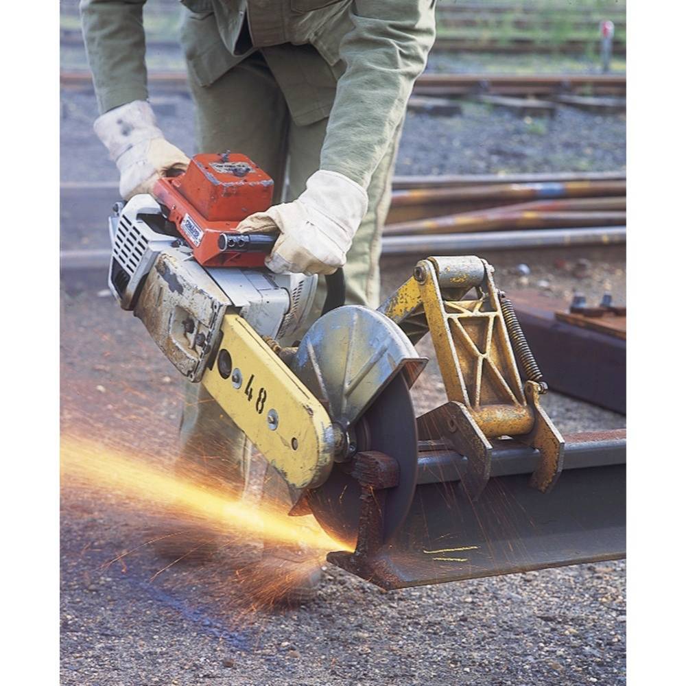 Une personne coupe un segment de poutre en acier avec une scie motorisée sur un chantier. Des étincelles volent dans toutes les directions.
