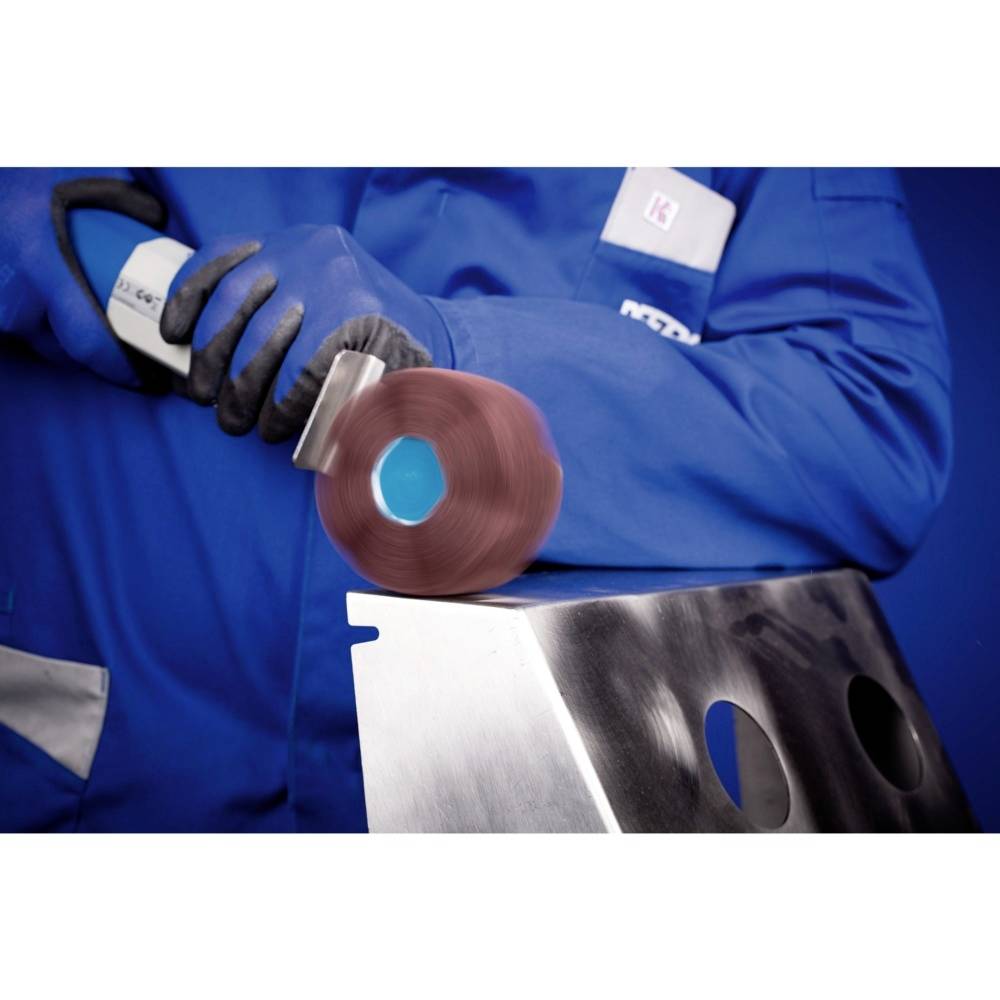 Une personne en tenue de travail bleue ponce une surface métallique avec un disque abrasif rotatif. Le focus est mis sur l'action.