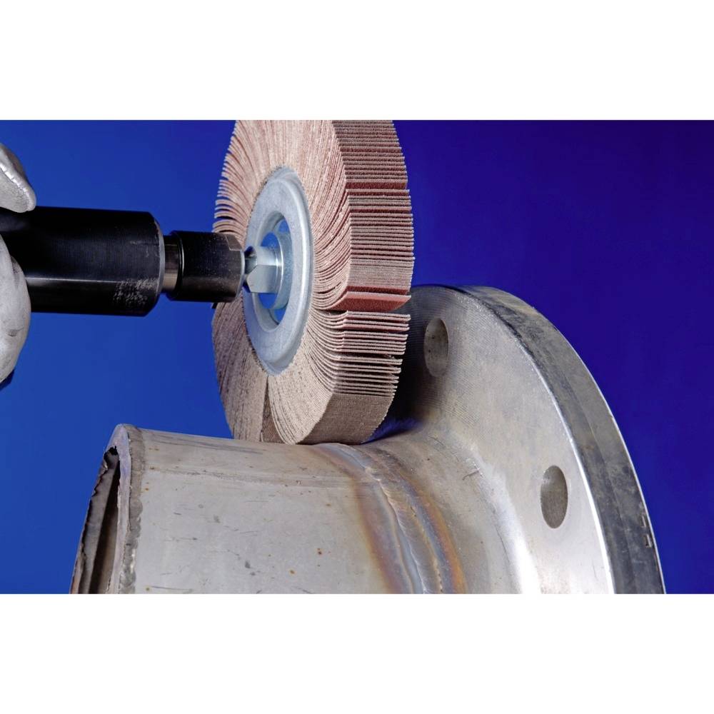 Une main tient un appareil de meulage dirigé vers un tube métallique. Un embout de ponçage est appliqué sur le tube pour polir sa surface.