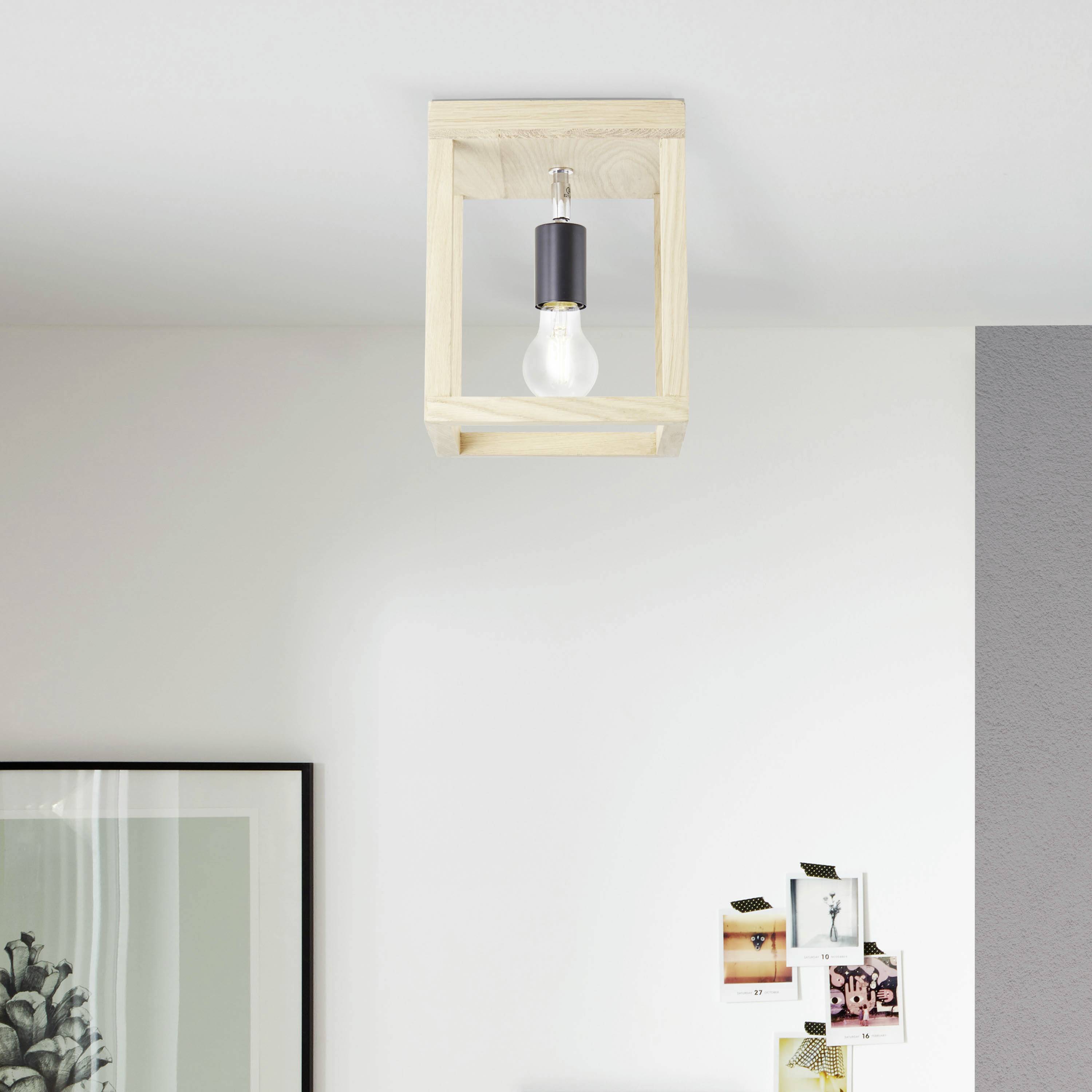 Une lampe de plafond avec un cadre en bois et une ampoule, montée sur un plafond blanc, à côté de photos et d'images accrochées au mur.