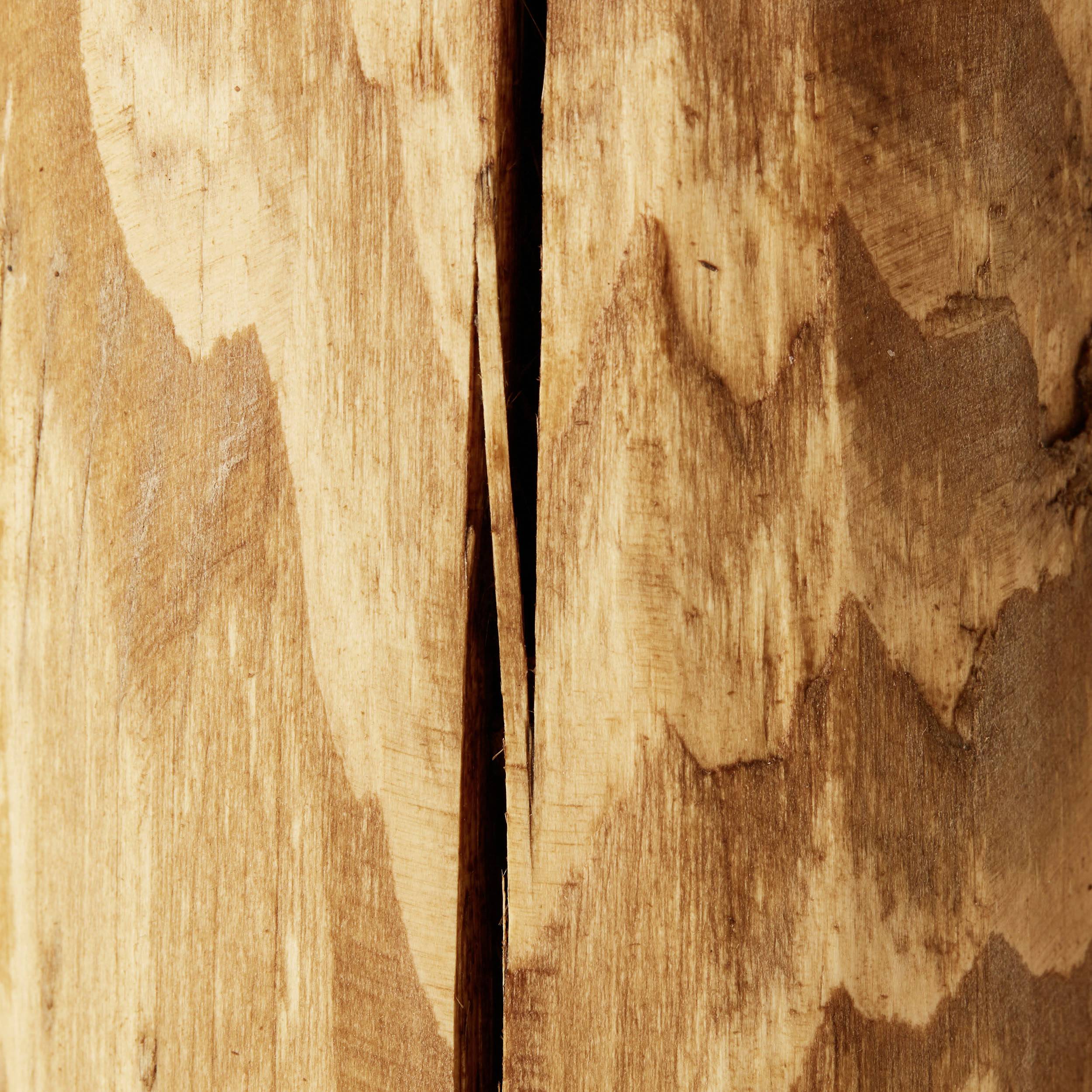 Surface en bois avec des veines naturelles et des fissures au centre, révélant la texture et l'âge du bois.