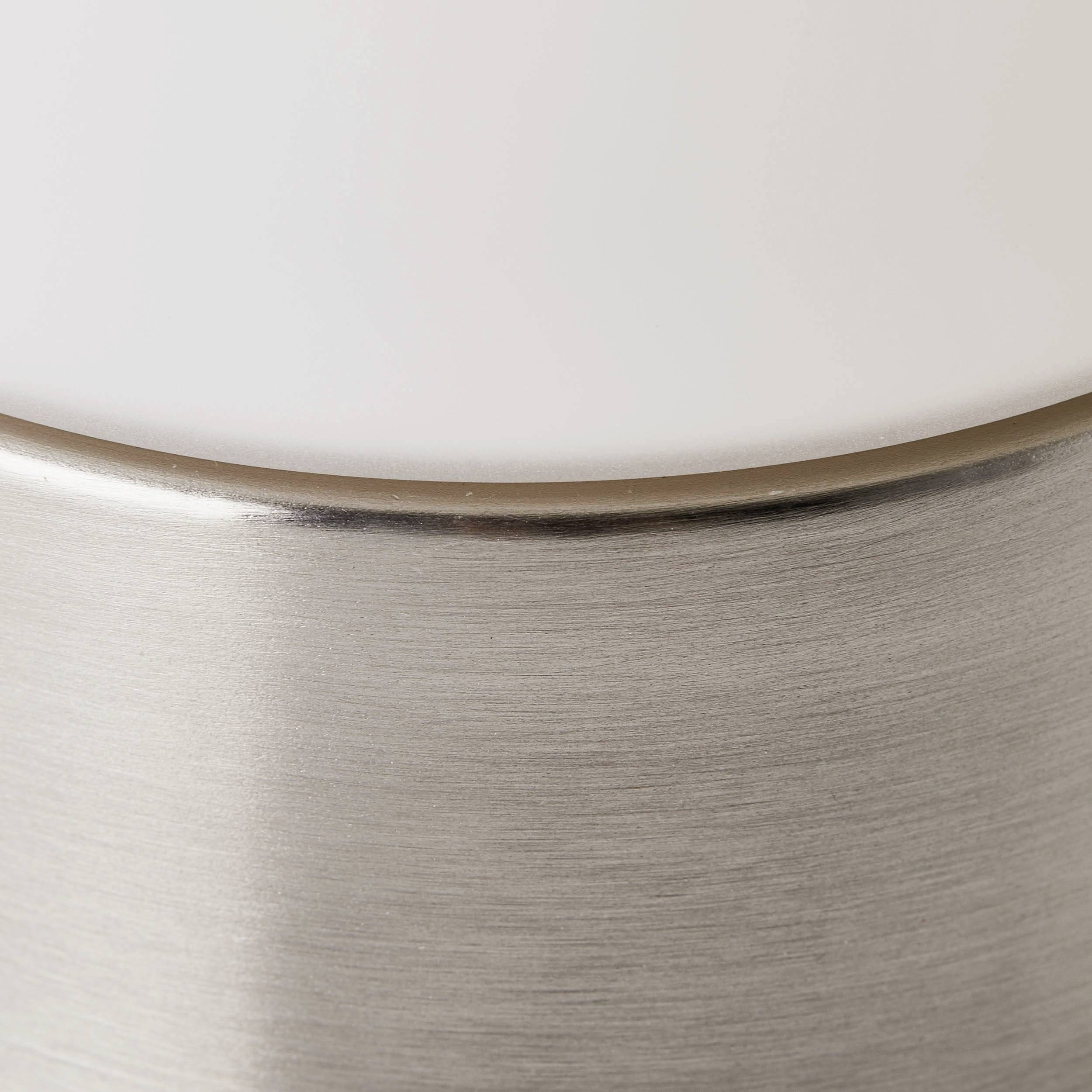 Gros plan sur une lampe moderne avec un dôme en verre dépoli blanc et un pied en métal argenté.