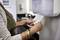Une personne retire un essuie-mains en papier d'un distributeur dans une salle de bain. Un lavabo est visible en arrière-plan.
