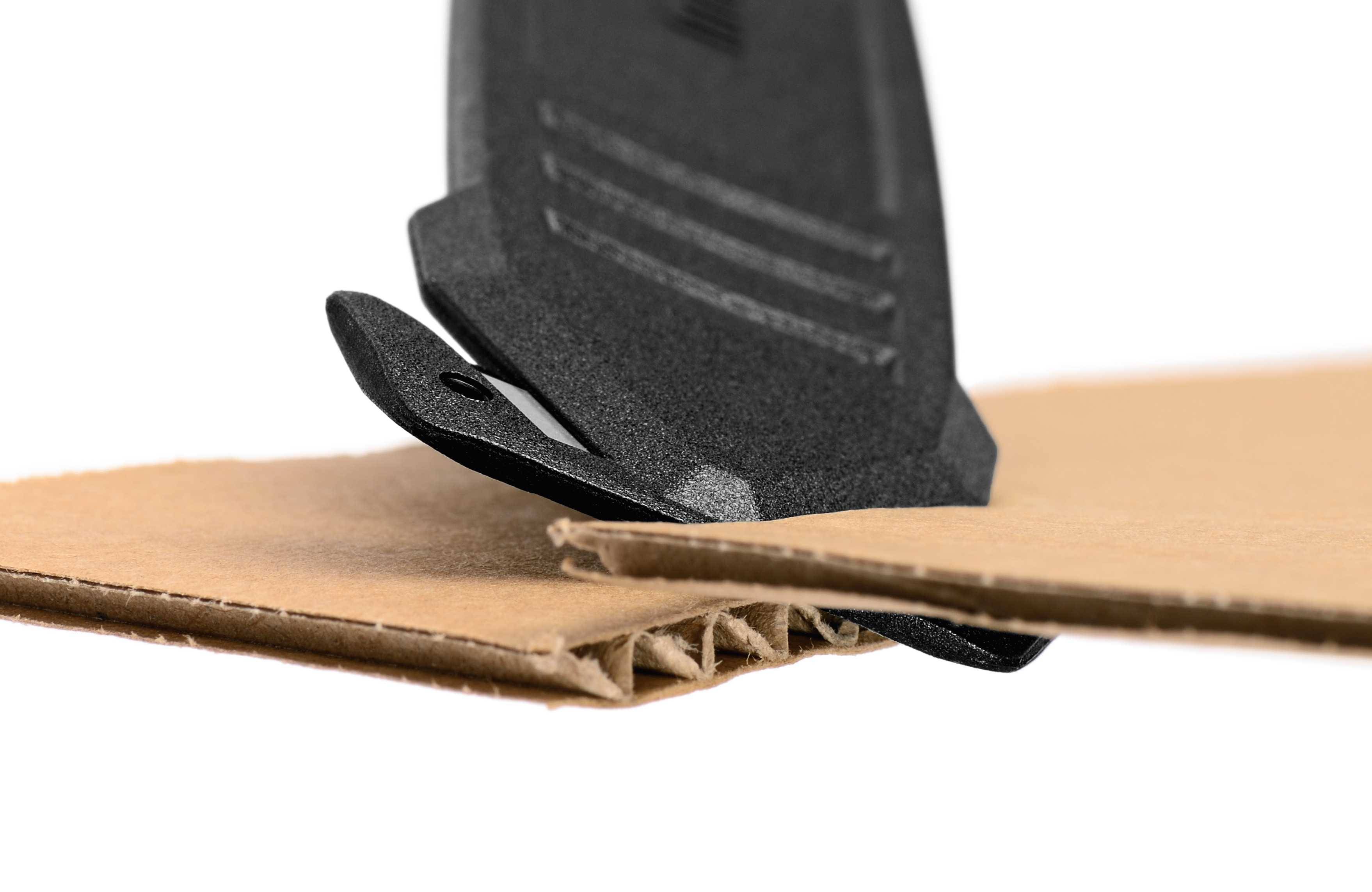 Un couteau coupe un tissu propre et sûr à travers du carton. L'image montre un gros plan de l'opération de coupe sur du carton ondulé.