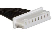 Fiche électrique blanche à cinq emplacements avec des câbles noirs.