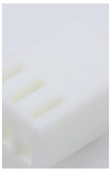 Une fiche en plastique blanc avec trois trous carrés, probablement destinée à des connexions électriques, posée sur une surface blanche.