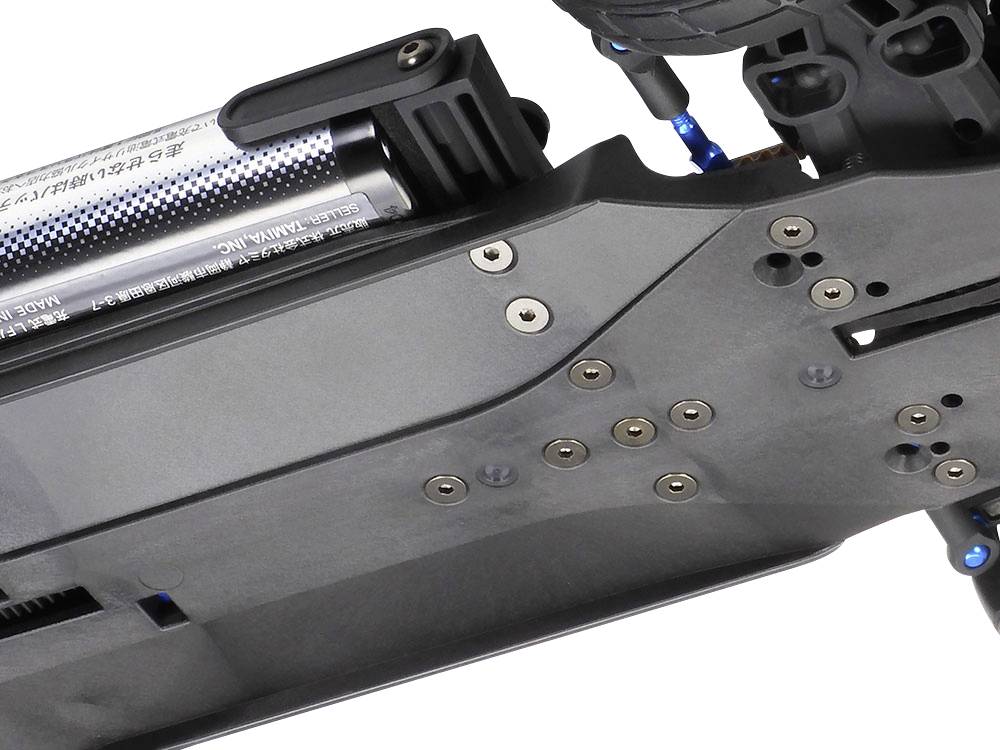 Gros plan d'un appareil électronique avec batterie visible, vis et câblage bleu, probablement un composant technique.