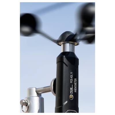 Gros plan d'un anémomètre à coupes avec un rotor noir tournant sur une station météorologique contre un ciel bleu.