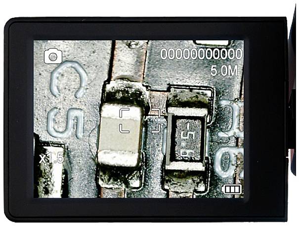 Gros plan d'une puce microélectronique sur un écran avec un affichage numérique de grossissement, révélant les détails fins des circuits électroniques.