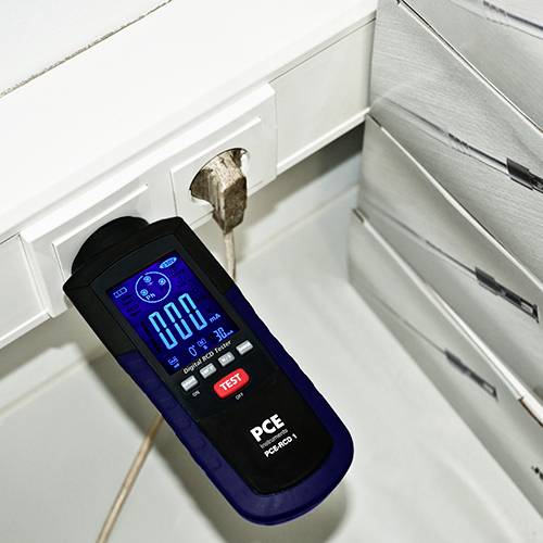 Un dispositif de test électrique est connecté à une prise électrique et affiche '0.00' sur son écran, représentant son état de mesure.