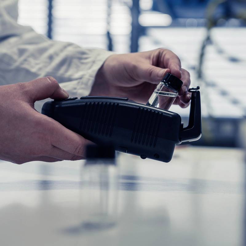 Un support de laboratoire tient une bouteille en verre à côté d'un appareil, illustrant une analyse ou une recherche expérimentale.