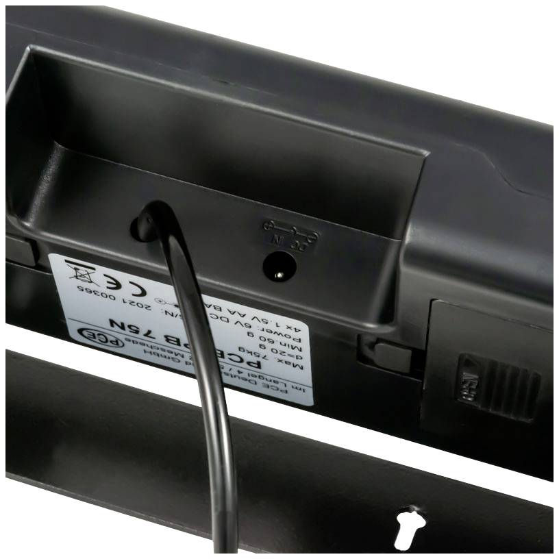 Une connexion de câble sur un appareil électronique, visible avec une étiquette comportant des spécifications techniques et des symboles.