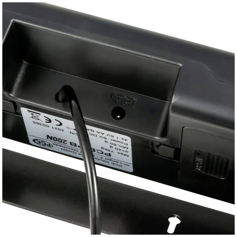 Une fiche de câble noire est branchée à l'arrière d'un appareil électronique qui peut être monté au mur.