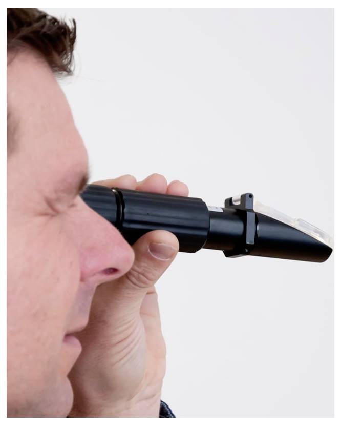 Gros plan d'un homme regardant dans un ophtalmoscope portatif lors d'un examen des yeux.