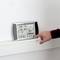 Une personne pointe du doigt un appareil de mesure électronique avec un affichage numérique. Des données de température, d'humidité et de pression sont visibles.