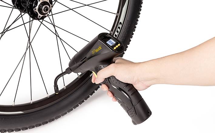 Une main utilise une pompe à air électrique pour gonfler le pneu d'un vélo.