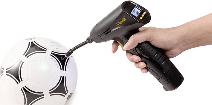 Une main tient une pompe à air qui gonfle un ballon de football noir et blanc.