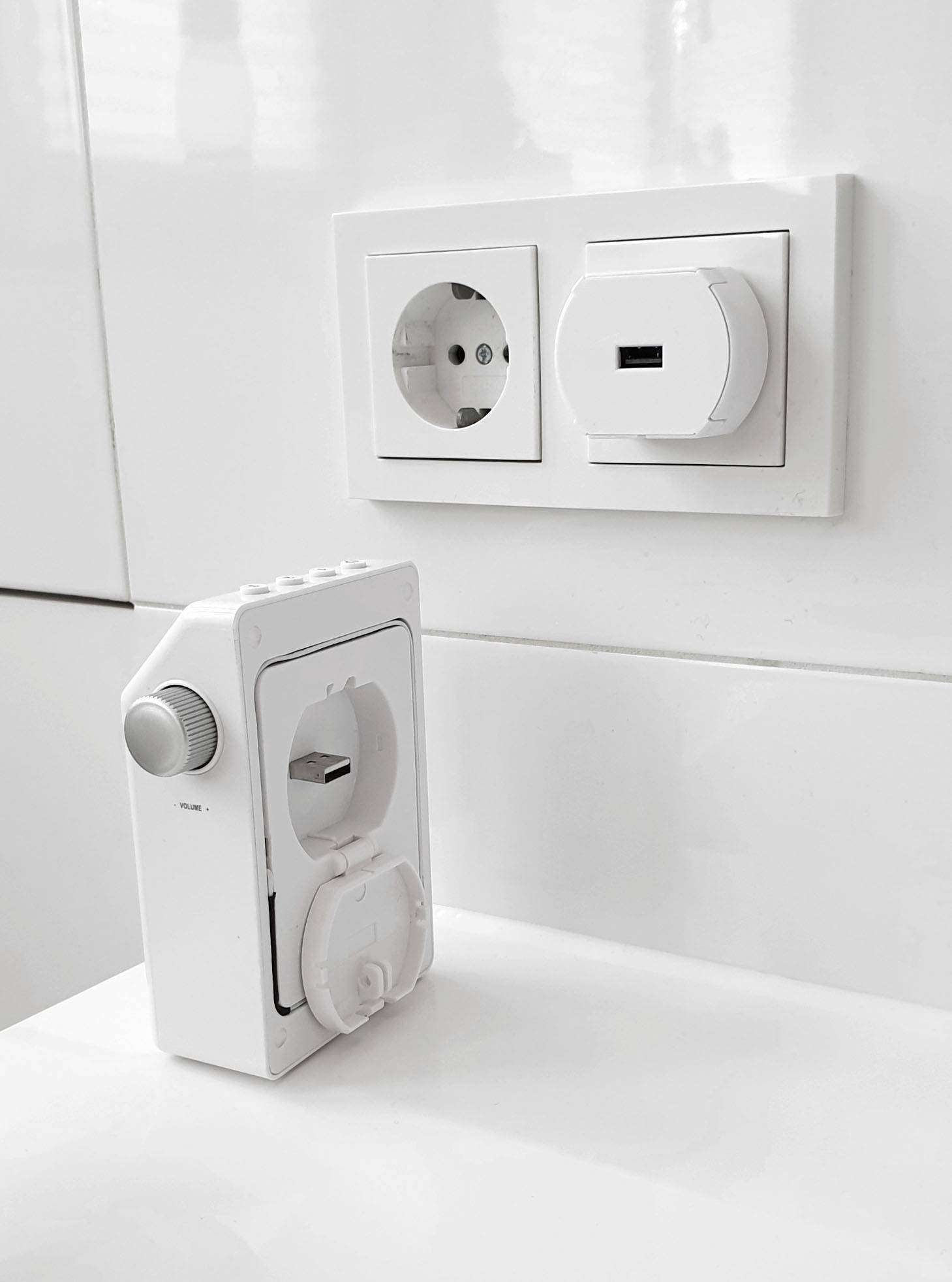 Une prise électrique européenne dans un mur blanc, avec une minuterie et un cache de sécurité à côté.