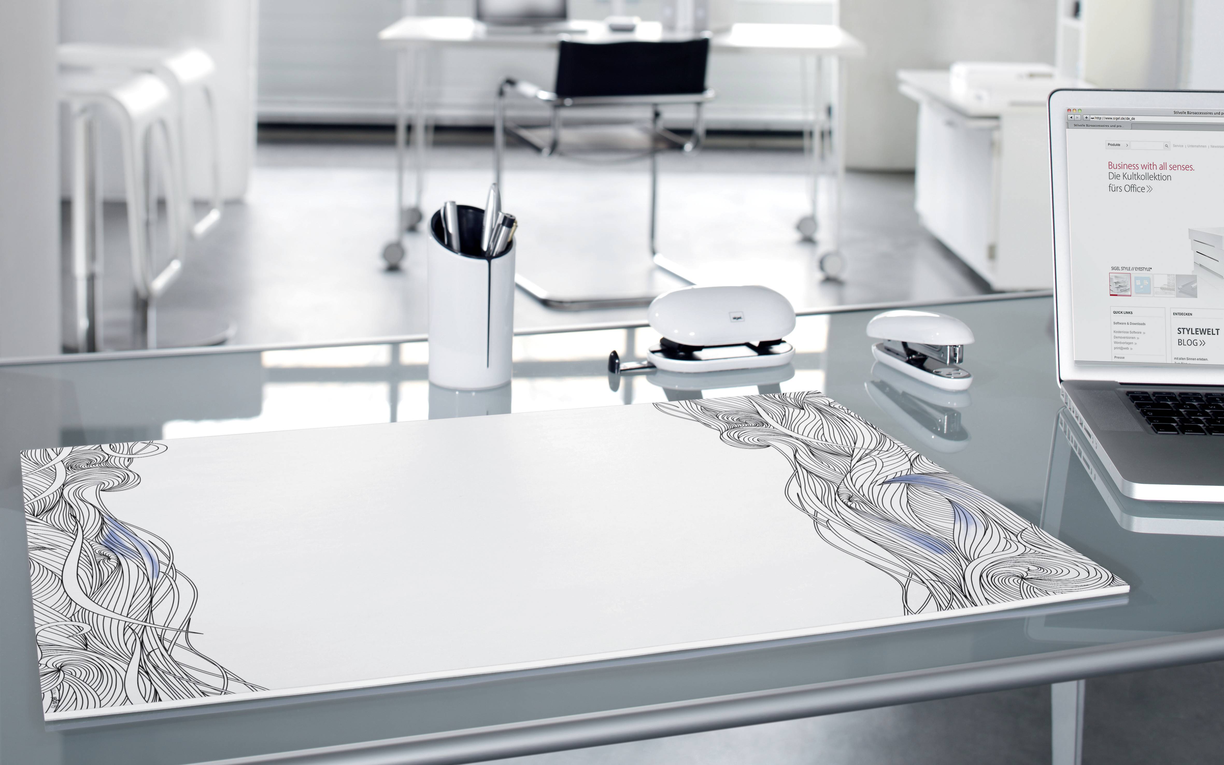 Un bureau moderne et minimaliste avec une surface en verre, un ordinateur portable, une souris et un support pour stylos à encre, dans un environnement de bureau neutre.