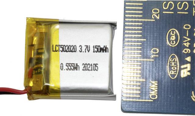 Petit accumulateur argenté à côté d'une règle. L'accumulateur est étiqueté '3,7V 150mAh', montrant les dimensions des spécifications techniques.