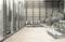 Installation industrielle avec de grands réservoirs métalliques et des canalisations dans un entrepôt. L'espace a une atmosphère industrielle avec des murs lisses et gris.