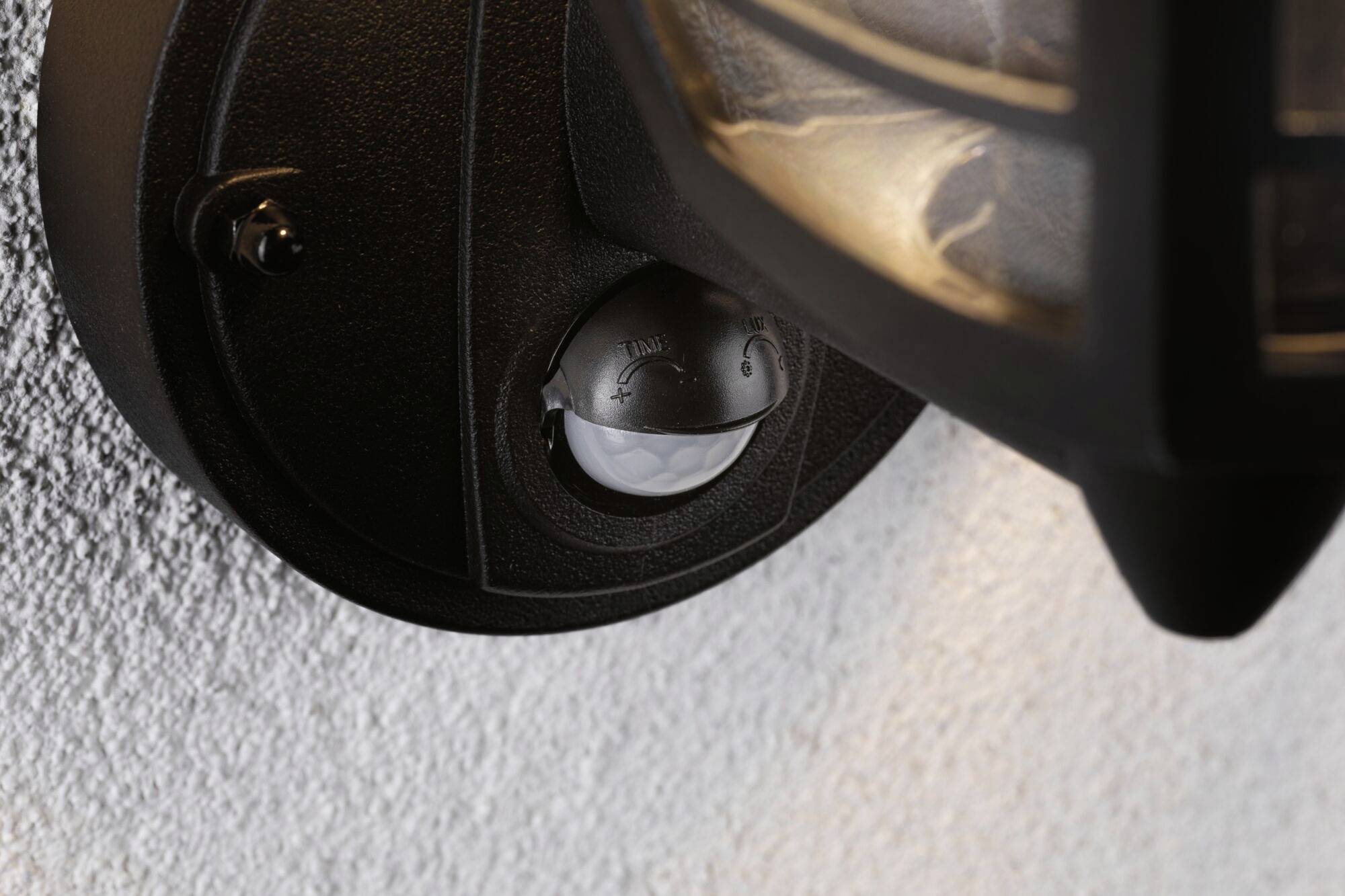 Détecteur de mouvement fixé sur un support de lampe murale indiquant le dispositif de détection de mouvements pour le contrôle automatique de l'éclairage.