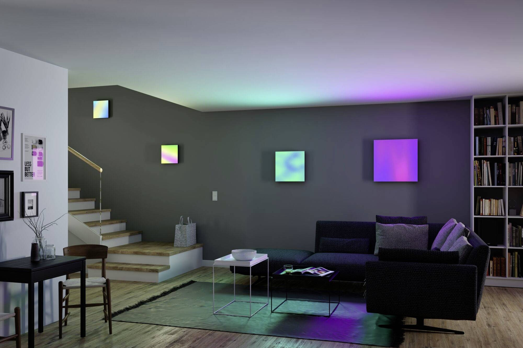 Salon moderne avec mur gris et éclairage de différentes couleurs. Canapé noir, étagère remplie de livres, escalier à gauche.