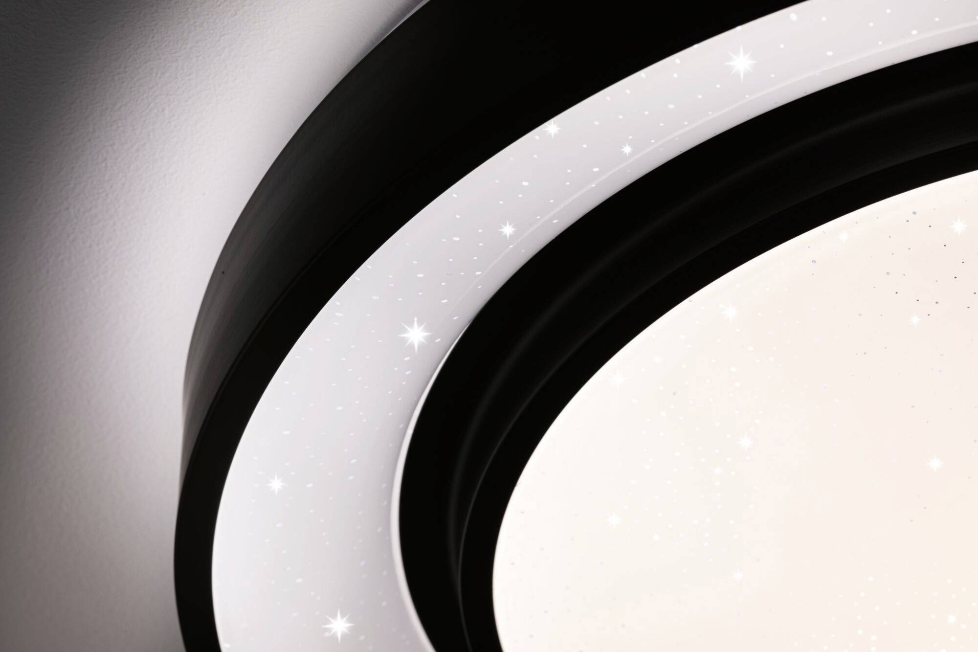 Un luminaire moderne au design cristallin, diffusant une lumière douce. La surface imite un ciel nocturne scintillant.