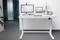 Un bureau debout moderne avec un ordinateur portable, deux écrans, un clavier et des décorations comme une plante dans un bureau.