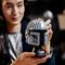 Une personne tient un modèle de casque LEGO de Star Wars dans ses mains, regardant de manière concentrée et intéressée, avec un arrière-plan flou.