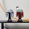 Deux casques de modèle LEGO de "Star Wars" sur une étagère. À gauche, un casque gris, à droite, un casque vert et rouge. Arc large en arrière-plan.
